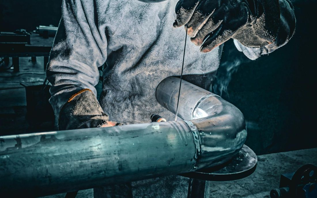 Welder fabricating pipe in workshop